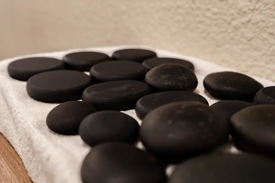 Smooth black basalt massage stones laid out on a white towel, ready to be heated