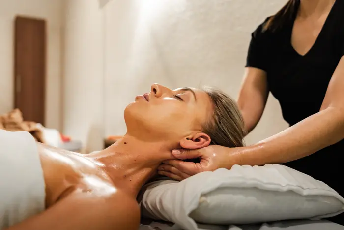 A therapist massages a relaxed client's neck and shoulders