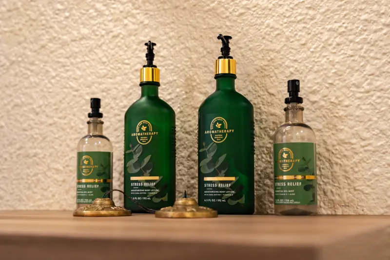 Massage oils in green glass bottles on a wooden shelf