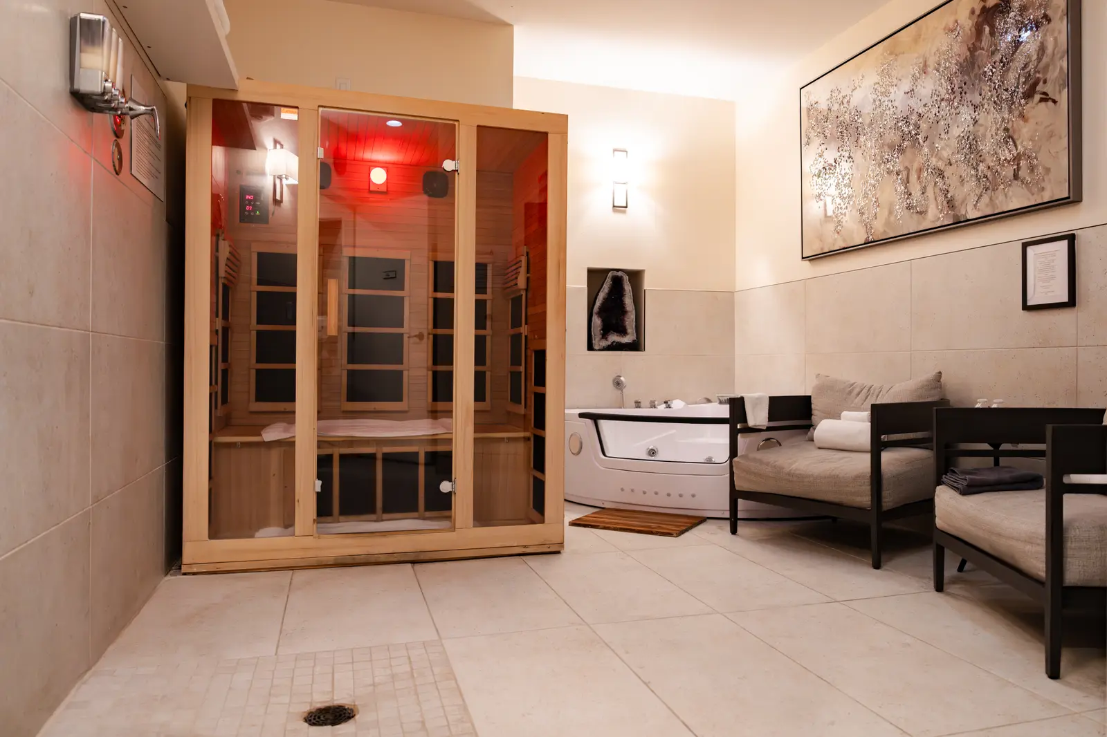 The private spa suite at Dean Martin: an infrared sauna glowing red beside a corner jet tub and two loungers